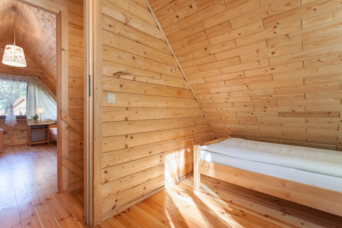 Houten vakantiekamer met eenpersoonsbed en schuin plafond bij Wooden holiday cottages Pobierowo in Duitsland.
