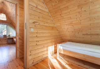 Gemütliches Holzferienhaus mit Einzelbett und Dachschräge bei Wooden holiday cottages Pobierowo in Deutschland.