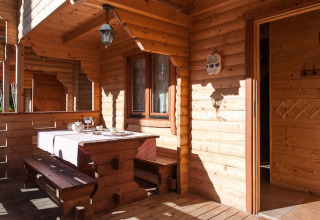 Houten terras bij Wooden holiday cottages Pobierowo met zitbank, gedekte tafel en zonlicht.