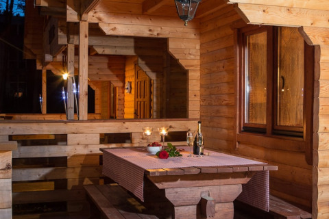 Veranda van houten vakantiewoning in Pobierowo, Duitsland, met gedekte tafel en kaarslicht.