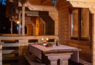 Houten chaletveranda in Pobierowo, Duitsland, met sfeervol gedekte tafel en kaarslicht voor de avond.