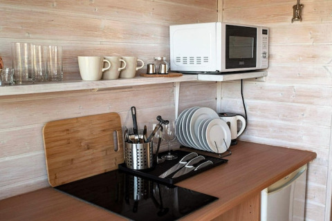 Kleine kitchenette met magnetron, bekers, glazen en borden in een houten hut in Duitsland.