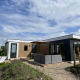 Moderne Zonneweelde Lodge XL ved Camping Zonneweelde i Holland med terrasse, sofa og liggestole udenfor.