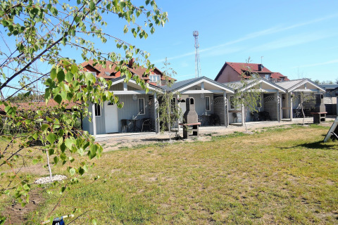 Buitenaanzicht van Aquarius Cottages in Duitsland met kleine huisjes, grasveld, bomen en tuinmeubilair.