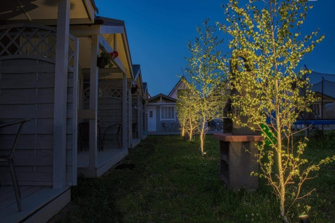 Nachtszene bei Aquarius Cottages für 2 Personen mit beleuchteten Bäumen und Holzterrassen in Deutschland.