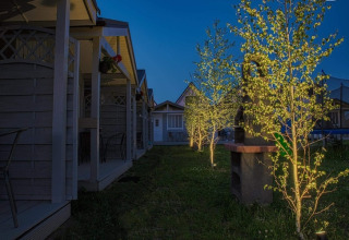Avondscène bij Aquarius Cottages voor 2 personen met verlichte bomen en veranda’s in Duitsland.
