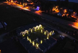 Nachtelijke luchtfoto van Aquarius Cottages in Duitsland met verlichte huisjes en straatverlichting.