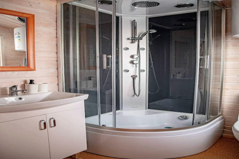 Modern bathroom at Aquarius Cottages in Germany, featuring a glass shower cabin and white sink unit.