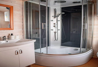 Modern bathroom at Aquarius Cottages in Germany, featuring a glass shower cabin and white sink unit.