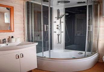 Salle de bain moderne à Aquarius Cottages en Allemagne, cabine de douche vitrée et lavabo blanc.