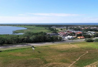 Uitzicht vanaf Aquarius Cottages op meer, bos, kustdorp en zee in Duitsland onder een zonnige hemel.