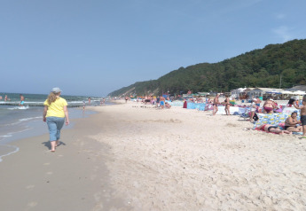 Personas disfrutan de un día soleado en la playa junto a colinas boscosas cerca de Aquarius Cottages en Alemania.