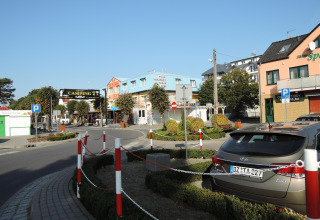 Straßenansicht nahe Aquarius Cottages mit geparkten Autos, Geschäften und Campingplatz, Deutschland