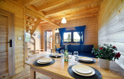 Licht houten interior in Lazurowy Zakątek lodge te Duitsland met gedekte tafel en blauwe gordijnen.