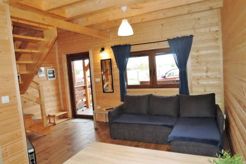 Woonruimte in lodge «Lazurowy Zakątek» in Duitsland met blauwe hoekzetel en houten interieur.