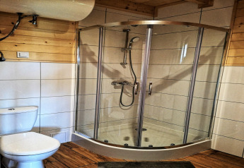 Modernes Bad mit Glasdusche, Toilette und Holzwänden, fotografiert in der Lazurowy Zakątek Lodge in Deutschland.