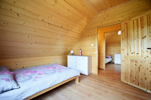 Dormitorio con paneles de madera, cama individual y cómoda blanca en Lazurowy Zakątek, Alemania.