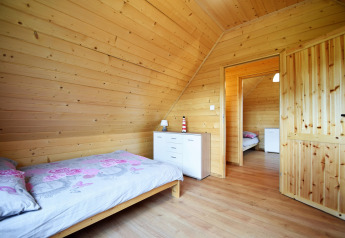 Dormitorio con paneles de madera, cama individual y cómoda blanca en Lazurowy Zakątek, Alemania.