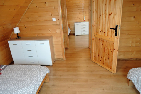 Heldere kamer in lodge Lazurowy Zakątek in Duitsland, met houten muren, twee bedden en kasten.