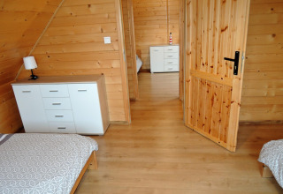 Heldere kamer in lodge Lazurowy Zakątek in Duitsland, met houten muren, twee bedden en kasten.