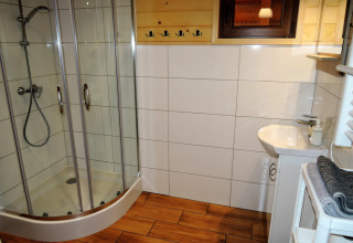 Baño moderno en Lazurowy Zakątek, Alemania, con ducha acristalada, lavabo pequeño y suelo de madera.