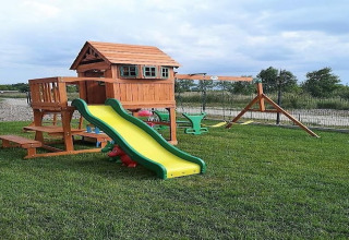 Buitenspeeltuin met houten huisje, glijbaan en schommels bij Lazurowy Zakątek-lodge in Duitsland.