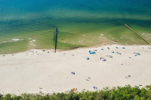 Vista aérea de una playa de arena con bañistas dispersos en Lazurowy Zakątek Lodge, junto al mar en Alemania.