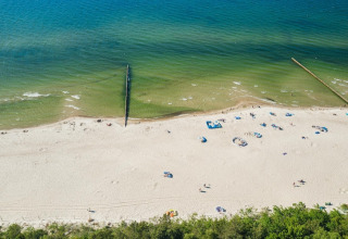 Vista aérea de una playa de arena con bañistas dispersos en Lazurowy Zakątek Lodge, junto al mar en Alemania.