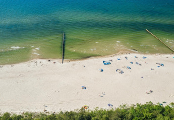 Vista aérea de una playa de arena con bañistas dispersos en Lazurowy Zakątek Lodge, junto al mar en Alemania.