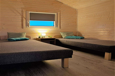 Houten kamer bij Aquarius Cottages in Duitsland met twee eenpersoonsbedden en warme verlichting.