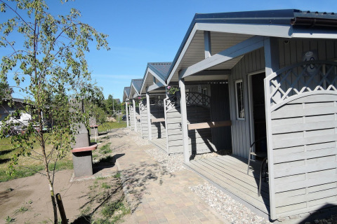 Rij lichte houten huisjes bij Aquarius Cottages in Duitsland met veranda’s en groene omgeving.