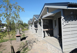 Rij lichte houten huisjes bij Aquarius Cottages in Duitsland met veranda’s en groene omgeving.