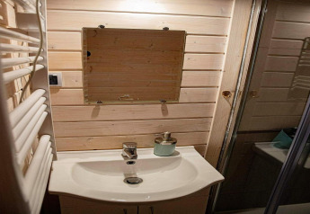Kleines Bad mit Holzverkleidung, Spiegel, Waschbecken und Seifenspender in Aquarius Cottages, Deutschland.