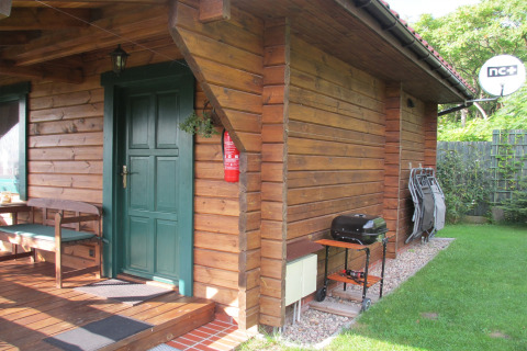 Sfeervol houten huisje met groene deur, veranda, barbecue en stoelen bij 'Charming house on a hill' in Duitsland.