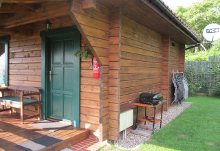 Sfeervol houten huisje met groene deur, veranda, barbecue en stoelen bij 'Charming house on a hill' in Duitsland.