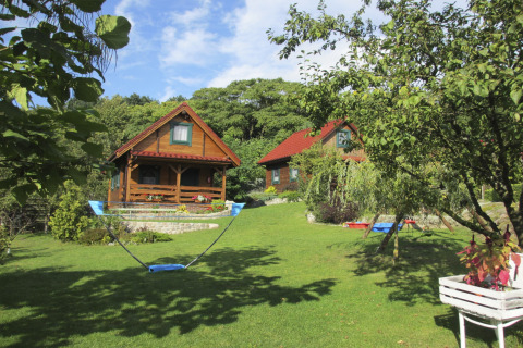 Sfeervolle houten huisjes op een heuvel met groene tuin en hangmat, zonnige dag in Duitsland.