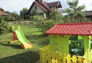 Speeltuin met glijbaan en speelhuisje in de tuin van een charmant huis op een heuvel in Duitsland.