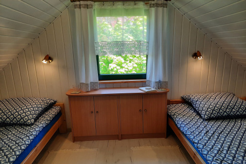 Knusse kamer met twee eenpersoonsbedden, raam en kast in het pension 'Charming house on a hill' in Duitsland.