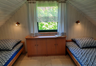 Knusse kamer met twee eenpersoonsbedden, raam en kast in het pension 'Charming house on a hill' in Duitsland.
