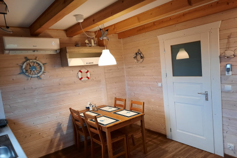 Eethoek met houten tafel, vier stoelen en nautische decoratie in 'House on a hill' lodge in Duitsland.