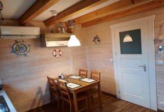 Eethoek met houten tafel, vier stoelen en nautische decoratie in 'House on a hill' lodge in Duitsland.