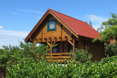 Houten lodge met rood dak en groene natuur bij House on a Hill in Duitsland onder blauwe lucht.