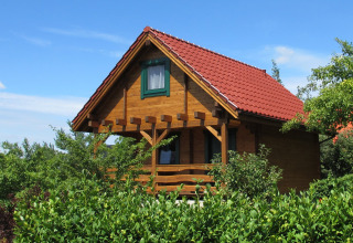 Houten lodge met rood dak en groene natuur bij House on a Hill in Duitsland onder blauwe lucht.