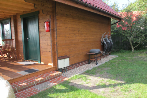 Houten lodge bij 'House on a hill' in Duitsland met veranda, barbecue en tuinstoelen in het gras.