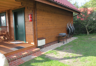 Houten lodge bij 'House on a hill' in Duitsland met veranda, barbecue en tuinstoelen in het gras.