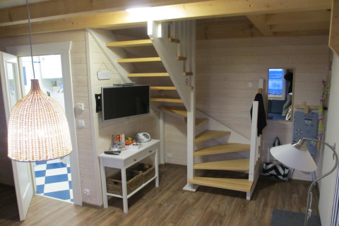 Interieur van lodge 'House on a hill' in Duitsland met houten trap, tv en moderne inrichting.