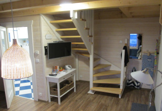Interieur van lodge 'House on a hill' in Duitsland met houten trap, tv en moderne inrichting.
