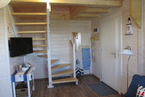 Ingang van lodge 'House on a hill' in Duitsland met trap, deur, tv en strijkplank in beeld.