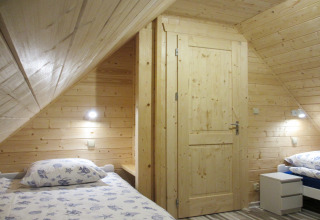 Houten slaapkamer met twee eenpersoonsbedden in lodge ‘House on a hill’ in Duitsland, sfeervol verlicht.