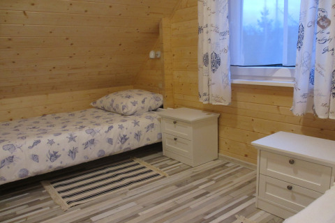 Knusse houten slaapkamer in lodge 'House on a hill' in Duitsland, met eenpersoonsbed en nachtkastjes.